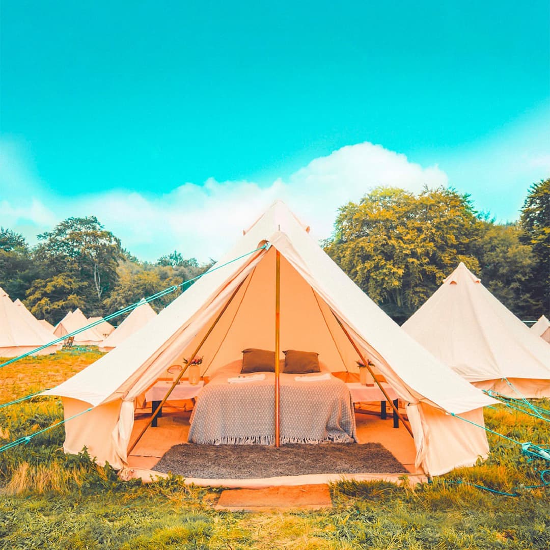 A bell tent with a double bed and side tables.