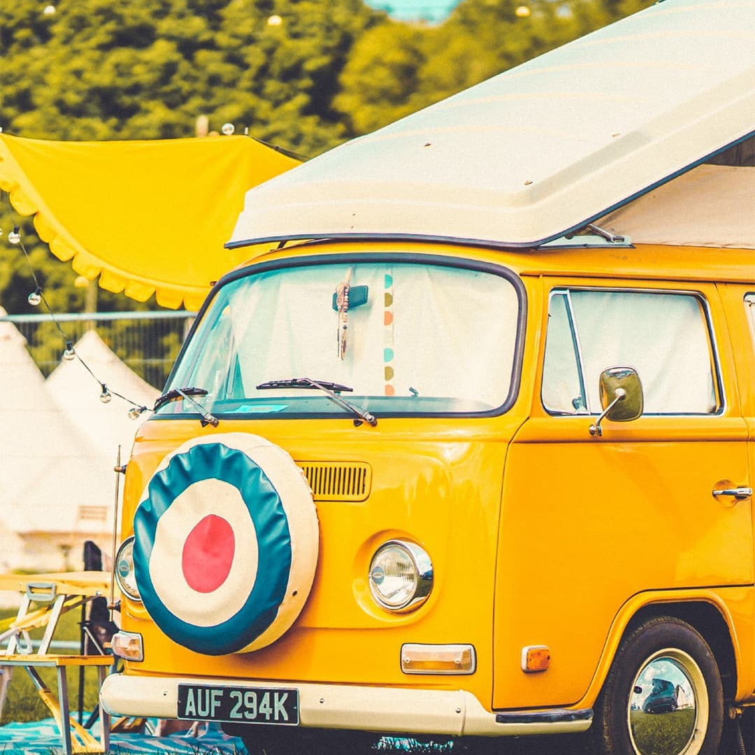 An old VW campervan parked in a field.