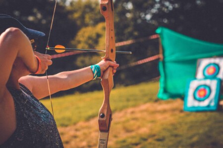 Bow and arrow at the archery activity at Camp Wildfire. A summer weekend break in a forest near London and Kent. An outdoor woodland retreat featuring adventure activities, live music, DJs, parties and camping. Half summer adventure activity camp, half music festival, for adults only.