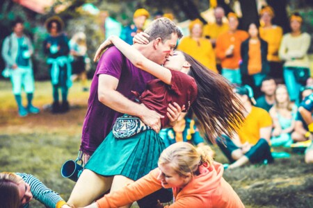 Patrol members kissing at Camp Wildfire. A summer weekend break in a forest near London and Kent. An outdoor woodland retreat featuring adventure activities, live music, DJs, parties and camping. Half summer adventure activity camp, half music festival, for adults only.