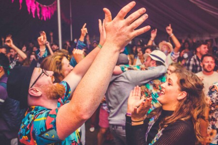 People having fun in the discotheque tent at Camp Wildfire. A summer weekend break in a forest near London and Kent. An outdoor woodland retreat featuring adventure activities, live music, DJs, parties and camping. Half summer adventure activity camp, half music festival, for adults only.