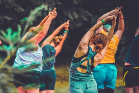 Group of people practising yoga at Camp Wildfire. The UK's Best Alternative Festival. UK's Top Unique Event. A summer weekend break in a forest near London and Kent. An outdoor woodland retreat featuring adventure activities, live music, DJs, parties and camping. Half summer adventure activity camp, half music festival, for adults only.