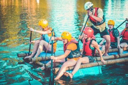 People on the raft they built on the lake at Camp Wildfire. A summer weekend break in a forest near London and Kent. An outdoor woodland retreat featuring adventure activities, live music, DJs, parties and camping. Half summer adventure activity camp, half music festival, for adults only.