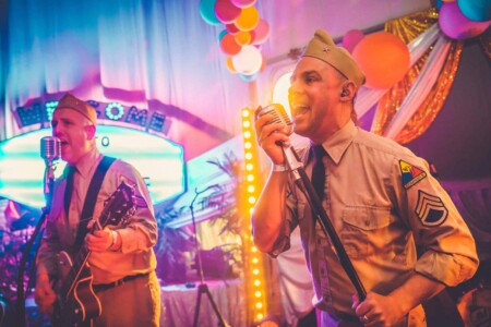 Members of Company B Swing singing on stage at Camp Wildfire. A summer weekend break in a forest near London and Kent. An outdoor woodland retreat featuring adventure activities, live music, DJs, parties and camping. Half summer adventure activity camp, half music festival, for adults only.