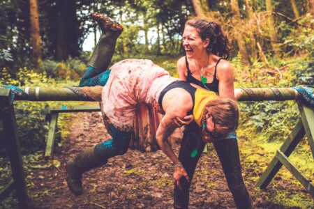 Two girls on the outdoor forest obstacle course. A summer weekend break in a forest near London and Kent. An outdoor woodland retreat featuring adventure activities, live music, DJs, parties and camping. Half summer adventure activity camp, half music festival, for adults only.