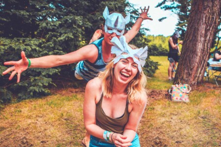 Couple with masks they made at Camp Wildfire. A summer weekend break in a forest near London and Kent. An outdoor woodland retreat featuring adventure activities, live music, DJs, parties and camping. Half summer adventure activity camp, half music festival, for adults only.