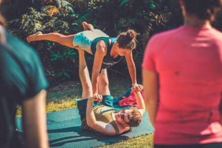 Acro yoga taking place in the sun outside at Camp Wildfire. A summer weekend break in a forest near London and Kent. An outdoor woodland retreat featuring adventure activities, live music, DJs, parties and camping. Half summer adventure activity camp, half music festival, for adults only.