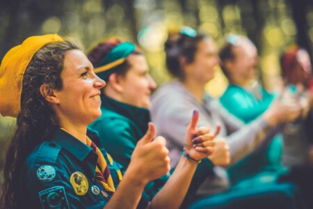 Girl in yellow hat giving a thumbs up in the sign language activity at Camp Wildfire. The UK's Best Alternative Festival. UK's Top Unique Event. A summer weekend break in a forest near London and Kent. An outdoor woodland retreat featuring adventure activities, live music, DJs, parties and camping. Half summer adventure activity camp, half music festival, for adults only.