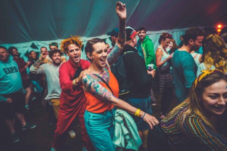 People partying on the dance floor at Camp Wildfire. A summer weekend break in a forest near London and Kent. An outdoor woodland retreat featuring adventure activities, live music, DJs, parties and camping. Half summer adventure activity camp, half music festival, for adults only.