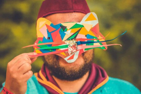 Guy with his patrol uniform on holding a colourful mask he made at the mask making activity at Camp Wildfire. The UK's Best Alternative Festival. UK's Top Unique Event. A summer weekend break in a forest near London and Kent. An outdoor woodland retreat featuring adventure activities, live music, DJs, parties and camping. Half summer adventure activity camp, half music festival, for adults only.