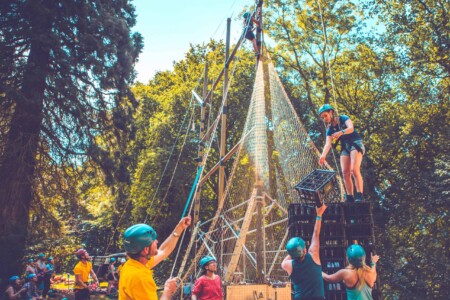 A group around the hire wires frame at Camp Wildfire. A summer weekend break in a forest near London and Kent. An outdoor woodland retreat featuring adventure activities, live music, DJs, parties and camping. Half summer adventure activity camp, half music festival, for adults only.