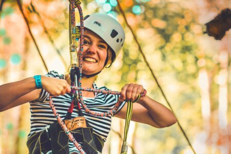 Girl with helmet and ropes on ready to go tree climbing at Camp Wildfire. The UK's Best Alternative Festival. UK's Top Unique Event. A summer weekend break in a forest near London and Kent. An outdoor woodland retreat featuring adventure activities, live music, DJs, parties and camping. Half summer adventure activity camp, half music festival, for adults only.