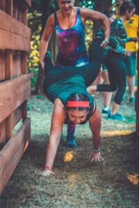 People doing the wheelbarrow at the obstacle course at Camp Wildfire. A summer weekend break in a forest near London and Kent. An outdoor woodland retreat featuring adventure activities, live music, DJs, parties and camping. Half summer adventure activity camp, half music festival, for adults only.