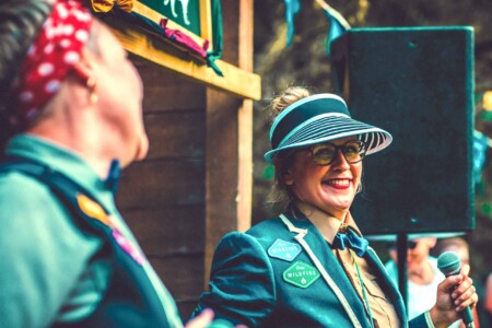 Umpire smiling with uniform on at Camp Wildfire. A summer weekend break in a forest near London and Kent. An outdoor woodland retreat featuring adventure activities, live music, DJs, parties and camping. Half summer adventure activity camp, half music festival, for adults only.