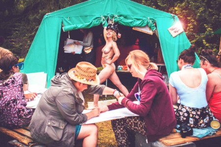 Naked model poses in life drawing session. A summer weekend break in a forest near London and Kent. An outdoor woodland retreat featuring adventure activities, live music, DJs, parties and camping. Half summer adventure activity camp, half music festival, for adults only.