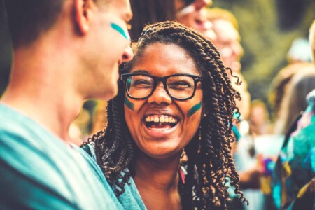 Girl smiling at Camp Wildfire. A summer weekend break in a forest near London and Kent. An outdoor woodland retreat featuring adventure activities, live music, DJs, parties and camping. Half summer adventure activity camp, half music festival, for adults only.